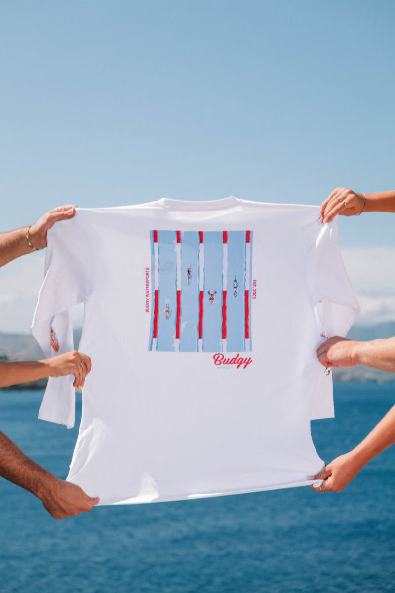White tee with swimming pool print held up by hands by the water 