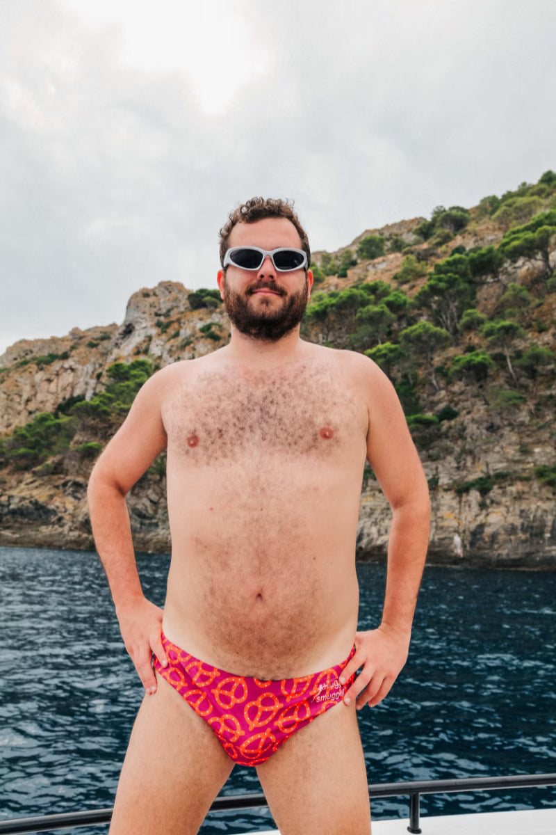 Red mens swim brief with a pretzel pattern  by the water 