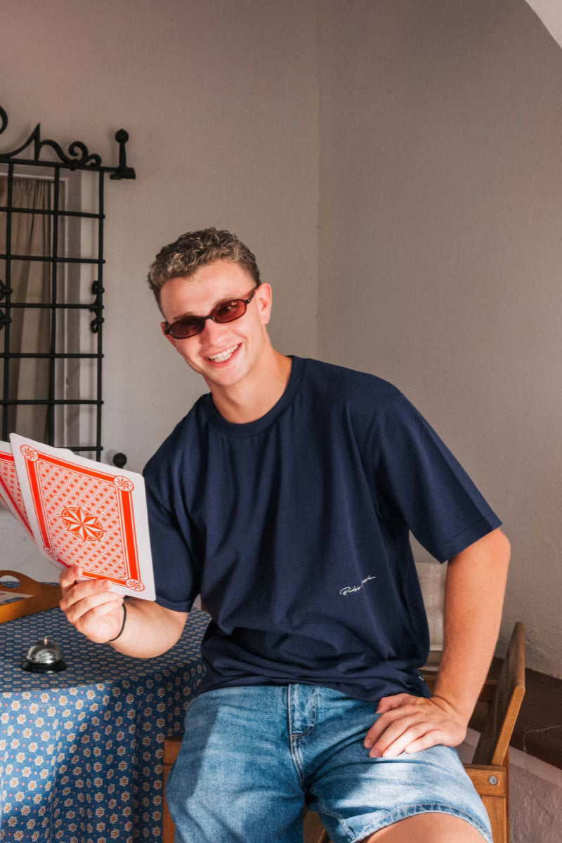Smiling man holding playing cards in the Heavyweight Navy Tee in Budgy